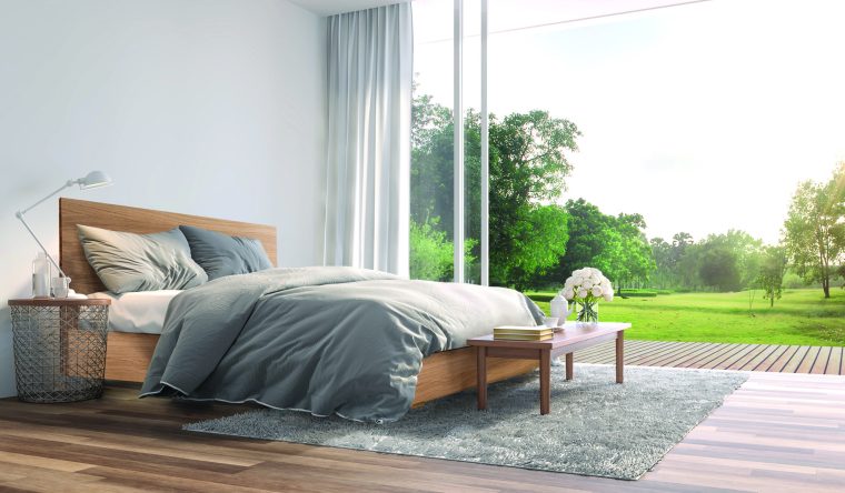 Modern bedroom 3d render.The Rooms have wooden floors ,decorate with gray fabric bed,There are large open sliding doors, Overlooks wooden terrace and big garden.